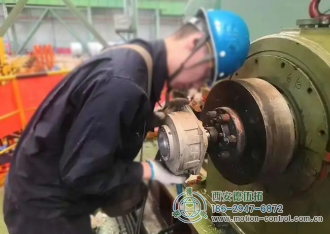 图为工人为彩涂酸轧轧机回装编码器的照片